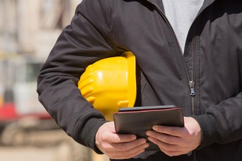 Davis-Bacon Act construction payroll construction worker holding screen managing Davis-Bacon software